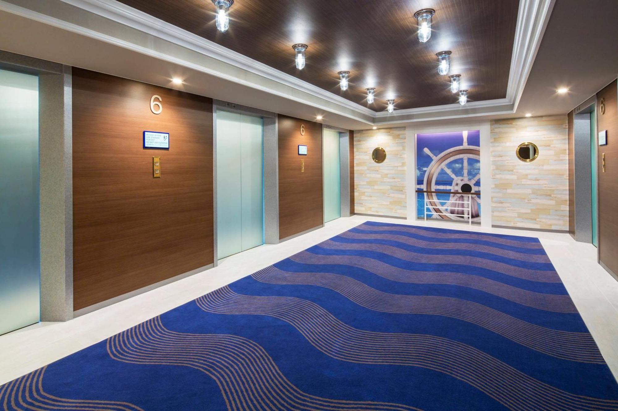Sheraton Grande Tokyo Bay Hotel Urayasu Dış mekan fotoğraf The photo shows a well-lit corridor with multiple elevators. The walls are a combination of wood and light-colored materials, giving a modern appearance. There are several round lights on the ceiling, enhancing the brightness of the area. The floorin
